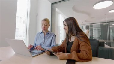 Çağdaş bir ofis ortamında, çeşitli ikili birlikte çalışarak, bir dizüstü bilgisayarın üzerinde işbirliği yaparken takım çalışmasını ve yeniliğini örnek alarak, profesyonel sinerji ve yaratıcılığın ilham verici bir sahnesini oluştururlar.