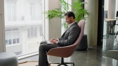 Modern ofis, kendini işine adamış birçok iş adamı, dizüstü bilgisayarı üzerinde şık bir sandalyede çalışıyor, tüm dikkatini gerektiren önemli sorumluluklarla meşgul.
