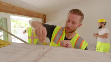 Afrika kökenli Amerikalı, İspanyol ve Kafkas kökenli çeşitli inşaatçılar ev yenilemesini geliştirmek, takım çalışmalarını ve adanmışlıklarını sergilemek için bir inşaat sahasında işbirliği yapıyorlar.