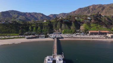 Yeşil tepeler ve sakin bir okyanus tarafından çerçevelenmiş Malibu İskelesi 'nin nefes kesici manzarasının tadını çıkarın. Bu manzara güzel bir şekilde sahili, doğal güzelliği ve olağanüstü manzarayı gözler önüne seriyor.