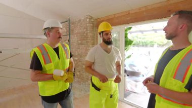 Güvenlik kaskı takan yetenekli müteahhit takımı, birlikte çalışma ve iletişimin hayati önem taşıdığı yoğun bir inşaat sahasında ev yenileme çalışmaları planlıyor ve yürütüyor.