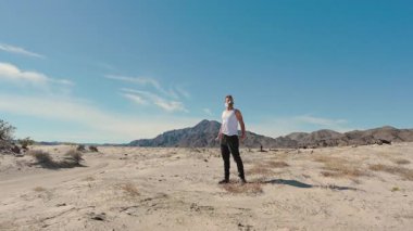 Issız bir adam, solunum maskesi takmış, uçsuz bucaksız, çorak bir çöl manzarasında kararlı bir şekilde duruyor. Bu da berrak, parlak mavi gökyüzünün arka planına karşı unutulmaz bir postapokaliptik ruh hali yaratıyor.