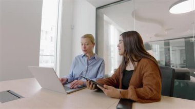 Modern bir ofiste, iki dinamik iş kadını iletişimi geliştirmek, üretkenliği artırmak ve girişimcilik ve profesyonel büyüme konusunda birbirlerine ilham vermek için dizüstü bilgisayarlar ve akıllı telefonlar ile işbirliği yaparlar.