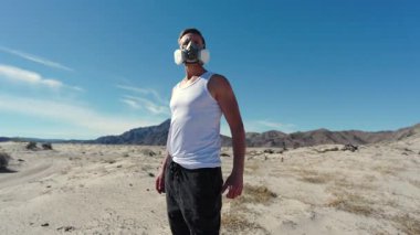 Sert bir çölde, solunum cihazı olan bir adam her yönden derin bir ıssızlığa karşı mücadelesini ve cesaretini gösteren kurak, çatlamış bir toprağı kıyamet sahnesine boyar.