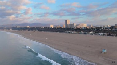 Los Angeles 'taki Santa Monica İskelesi' nin çarpıcı hava manzarasının tadını çıkarın. Kıyı şeridi, sabah dalgaları çöker, okyanus dalgaları dalgalanır ve renkli eğlence gezileri eğlence ve macera arayan sayısız ziyaretçiyi çeker.