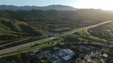 Los Angeles banliyölerinin havadan görünüşü parlak yeşil tepeleri, görkemli dağları ve işlek otobanı ön plana çıkarıyor. Hepsi de altın saat boyunca çarpıcı detaylarla yakalanmış, ılık günbatımı renkleriyle yıkanmış.