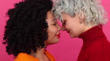 Kafkas ve Afrikalı Amerikalı kadınların sarılıp öpüşmelerini yakından çek. Birbirine bakan LGBT çifti portresi. Yüksek kalite 4k görüntü