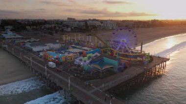 Santa Monica 12.14.2024 hava manzarası ikonik Santa Monica İskelesi 'ni yakalıyor, çarpan okyanus dalgaları arasında canlı yolculukları vurguluyor, nefes kesen Kaliforniya kıyı şeridini gösteriyor. Los Angeles demek. ABD