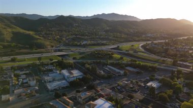 Los Angeles banliyösünün çarpıcı görüntüsü, yemyeşil tepeler, otoban trafiği ve güzel bir gün batımı.