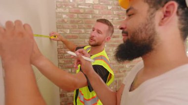 Deneyimli bir müteahhit ekibi, ekip çalışması ile dolu yoğun bir inşaat sahasında gelişmiş araçlar ve etkin planlama kullanarak bir ev yenileme projesinde işbirliği içinde yer alıyor.