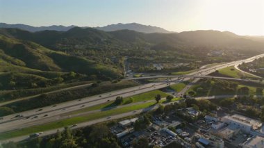 Hava görüntüleri güzel bir şekilde Los Angeles banliyösünü yakalıyor, yemyeşil tepeler sergileniyor, yoğun bir çevre yolu, ve çarpıcı bir günbatımı, kentsel yaşamı doğayla mükemmel bir uyum içinde harmanlıyor.