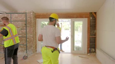 Çeşitli ve yetenekli müteahhitler, özel aletleri ve detaylı planlarıyla yeni bir evi yenilemeye ve geliştirmeye odaklanmış bir inşaat sahasında birlikte çalışıyorlar.