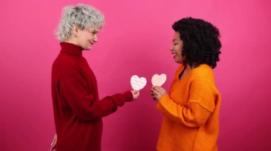 Sevgililer Günü kartlarını birbirlerine sunan LGBT çifti yakından görülüyor. Romantik bayramı kutlarken kız arkadaşlar öpüşüyor ve sarılıyorlar. Yüksek kalite 4k görüntü