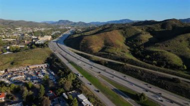 Çarpıcı hava aracı görüntüleri Los Angeles 'ın geniş banliyö manzarasını, yemyeşil tepeleri, işlek otobanları ve izleyicileri büyüleyen büyüleyici bir günbatımını gözler önüne seriyor.