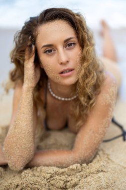 Genç bir kadın, Hawaii 'de güzel kumlu bir plajda zarifçe poz veriyor. Etrafı nefes kesen doğal güzellik ve yumuşak okyanus dalgalarıyla çevrili. Yazın huzurlu ve kaygısız ruhunu somutlaştırıyor.