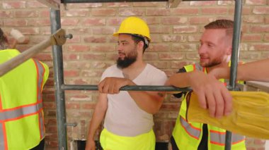 Aralarında Afro-Amerikan, İspanyol ve Kafkas işçilerinin de yer aldığı çeşitli inşaatçılar, bir inşaat sahasında ev yenileme çalışmasında işbirliği yaparak takım çalışması ve coşku sergilediler..