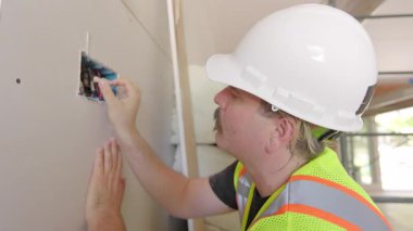 Güvenlik kaskı takan yetenekli bir müteahhit, ev iyileştirme projeleri yoluyla toplumları iyileştirmek için hayati önem taşıyan kabloları ve özel becerileri tamir eden bir inşaat sahası restore ediyor.