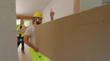 Hepsi de güvenlik kaskı takmış çeşitli müteahhitler, kalabalık bir inşaat sahasında heyecan verici bir ev yenileme çalışmasında, etkileyici bir takım çalışması ve uzmanlık sergileyerek iş birliği yapıyorlar.