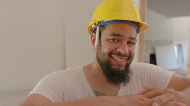 Parlak sarı bir şapkayla gülümseyen neşeli inşaat işçisi, yoğun bir yenileme sahasında yeteneklerini sergiliyor. İşindeki kararlılığını, neşesini ve çeşitli görevlerde başkalarıyla takım çalışmasını yansıtıyor.