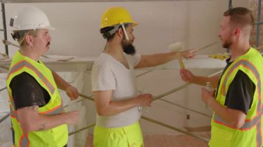 Yoğun bir inşaat alanında, çeşitli geçmişlerden üç inşaatçı yenilikçi yenileme planlarını tartışıyor, takım çalışmalarını ön plana çıkarıyor ve ev yenileme sürecindeki çeşitliliği kutluyor