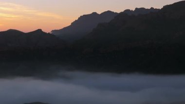 Bu hava görüntüleri gün batımında büyüleyici Malibu dağlarını yakalıyor, sisle örtülmüş ve dönen bulutlarla çevrili, nefes kesici doğanın huzur verici güzelliğini gözler önüne seriyor