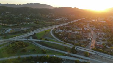 Los Angeles banliyölerinin nefes kesici hava manzaralarını keşfedin. Yeşil tepelerin çarpıcı bir günbatımı altında yoğun otoyollarla buluştuğu ve doğa ile şehir yaşamı arasındaki dinamik ilişkiyi yakaladığı yerler.