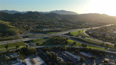 Sersemletici hava aracı görüntüleri Los Angeles 'ın banliyösünde yeşil tepelerle çevrelenmiş bir otoyol kavşağını ve güzel manzarayı güzelleştiren büyüleyici günbatımını gösteriyor.