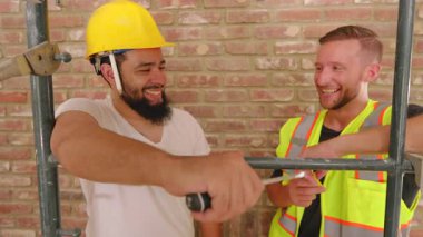 Canlı bir inşaat sahasında, çeşitli geçmişlerden iki inşaatçı araçlar ve planlama, yaratıcılık, adanmışlık ve güvenliğe ve takım çalışmasına bağlılığı vurgulamak üzerinde işbirliği yapmaktadır.