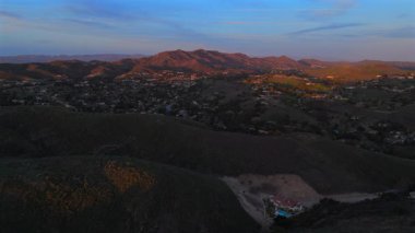 Çarpıcı insansız hava aracı görüntülerinde Los Angeles Malibu dağları, yemyeşil tepeler, kabarık bulutlar ve büyüleyici günbatımı manzaraları var.