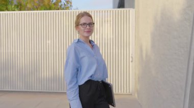 Gözlüklü, kendine güvenen bir iş kadını dizüstü bilgisayarıyla şık bir şekilde dışarıda duruyor. Kariyer hedefleri ve girişimci ruhu üzerine profesyonel tarzını ve hırsını sergiliyor.