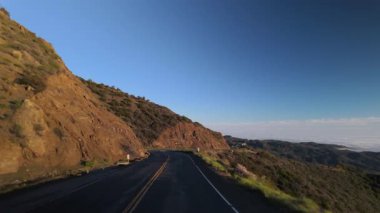 Çarpıcı sürüş görüntüleri, gün batımında Malibu dağlarının nefes kesici güzelliğini, yemyeşil tepeleri ve yumuşak, ruhani sisi yakalar.