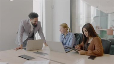 Yetenekli profesyonellerden oluşan canlı ve çeşitli bir grup, hedeflerine ulaşmak için dizüstü bilgisayarları ve tabletleriyle çalışmaya odaklanmış, parlak ve modern bir ofis ortamında aktif olarak işbirliği yapıyor.