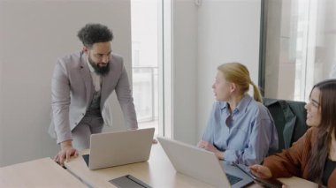 Çağdaş bir ofis ortamında, üretken bir toplantı sırasında çeşitli yetenekli profesyonellerden oluşan bir grup, her biri laptoplarına odaklanmış ve çeşitli yenilikçi fikirleri aktif olarak tartışıyor.