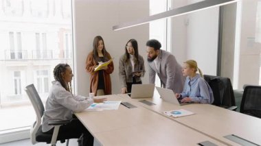 Çeşitli ve yetenekli profesyonellerden oluşan bir grubun modern bir ofis ortamında işbirliği yaptığı, etkili bir takım çalışması sergilediği ve enerjik ve dinamik bir çalışma ortamında yenilikleri teşvik ettiği görülüyor.