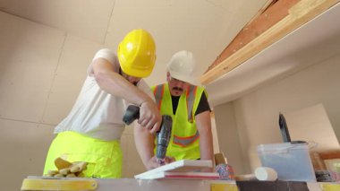 Önemli bir yenileme projesinde çalışan iki yetenekli inşaat işçisi, sondaj da dahil olmak üzere çeşitli elektrikli aletler kullanıyorlar.. 
