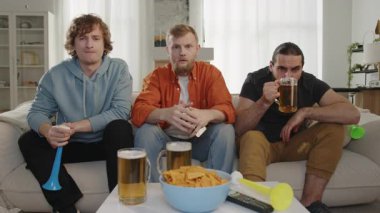 Erkekler televizyonda maç izleyip, bira içip, cips yiyorlar. Avrupa ve Dünya Futbol Kupası, Almanya, ABD, Kanada, Meksika. Futbol, Paris oyunları, spor ve futbol fanatikleri