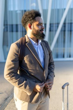 Özel dikim takım elbiseli şık bir adam modern mimarinin önünde dikilip profesyonellik ve kentsel kültürün bir karışımını sergileyerek dikkatleri üzerine çekiyor.