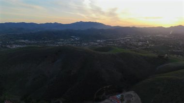 Los Angeles 'taki Malibu dağlarının büyüleyici güzelliğini deneyimleyin, yemyeşil tepeler ve günbatımı bulutları, büyüleyici hava aracı görüntülerinde bu manzarayı gösteriyor.