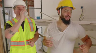 Çeşitli geçmişlerden çeşitli inşaatçılar kalabalık bir inşaat sahasında sevinçle bir araya gelerek, araçlar ve takım çalışması kullanarak yeni bir evin yenilenmesini hevesle planlıyorlar.