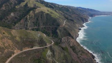 Büyük Sur 'un bu hava manzarası, Kaliforniya kıyı şeridi boyunca kıvrılan 1. Karayolu' nu gösteriyor. Muhteşem dağların ortasında tek bir araba ve büyüleyici okyanus manzarası.