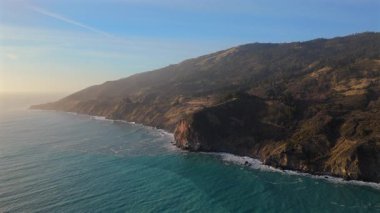 Kaliforniya 'nın nefes kesen Big Sur bölgesini çeken hava fotoğrafında, gün batımında baş döndürücü uçurumların etrafında esen 1. Otoyol manzaranın dingin güzelliğini gözler önüne seriyor.
