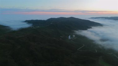 Malibus görkemli dağlarının çarpıcı insansız hava aracı görüntüleri, canlı yeşil tepeler ve günbatımında büyüleyici sis, huzur hissi veren nefes kesici bir panoramik manzara yaratıyor.