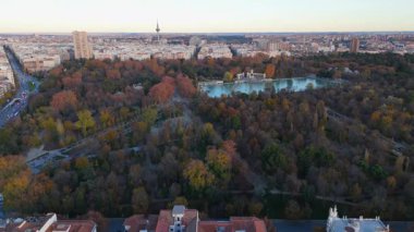 Muhteşem bir El Retiro sonbahar parkını yakalayan nefes kesici görüntülerin tadını çıkarın. Resimli arka planda etkileyici bir şehir siluetinin yanında dingin, pırıl pırıl bir göl de var.
