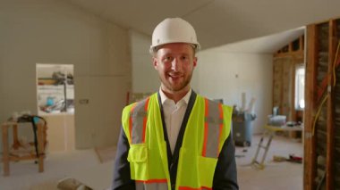 Son derece yetenekli bir inşaat yöneticisi kısmen yenilenmiş bir binada dururken kendine güvenerek gülümsüyor. Uygun güvenlik ekipmanları giyiyor ve tüm projeyi titizlikle denetliyor.