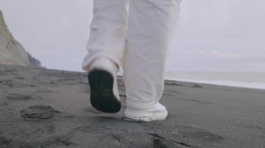Huzurlu ve sakin bir sahne nefis bir siyah kumsal boyunca sakin bir şekilde gezinen bir bireyi tasvir ediyor, büyüleyici, yüksek uçurumlar ve sakin, davetkar bir deniz tarafından özenle kucaklanıyor.