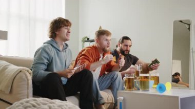 Bir grup taraftar TV 'de futbol maçı izliyor, bira içiyor ve cips yiyor, golü kutluyor. Avrupa ve Dünya Futbol Kupası, Almanya, ABD, Kanada, Meksika. Spor ve futbol hayranları. Yavaş Mo