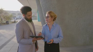 Canlı bir şehirde, Afrikalı bir Amerikalı işadamı ve iş kadını bir tablet üzerinde işbirliği yaparak, yaratıcılığı ve takım çalışmasını teşvik eden modern bir açık hava ortamında yenilikçi fikirleri paylaşıyor.
