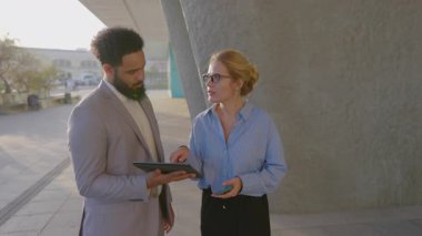 Canlı bir şehirde, Afrikalı bir Amerikalı işadamı ve iş kadını bir tablet üzerinde işbirliği yaparak, yaratıcılığı ve takım çalışmasını teşvik eden modern bir açık hava ortamında yenilikçi fikirleri paylaşıyor.