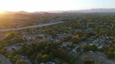 Çarpıcı hava görüntüleri, Los Angeles 'ın banliyö manzarasını güzel bir şekilde gösteriyor. Çevre yolu trafiğini, yemyeşil tepeleri ve ufukta soluk kesici ve sakin günbatımı manzarasını yakalıyor.