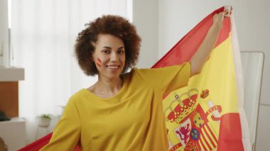Mutlu İspanyol futbol fanatiği, yanaklarında boyalı bayraklarla favori İspanya takımı için tezahürat yapıyor. Avrupa spor futbolu. Futbol kupası 2026 ABD, Kanada, Meksika. Spor ve futbol hayranları. Yavaş Hareket